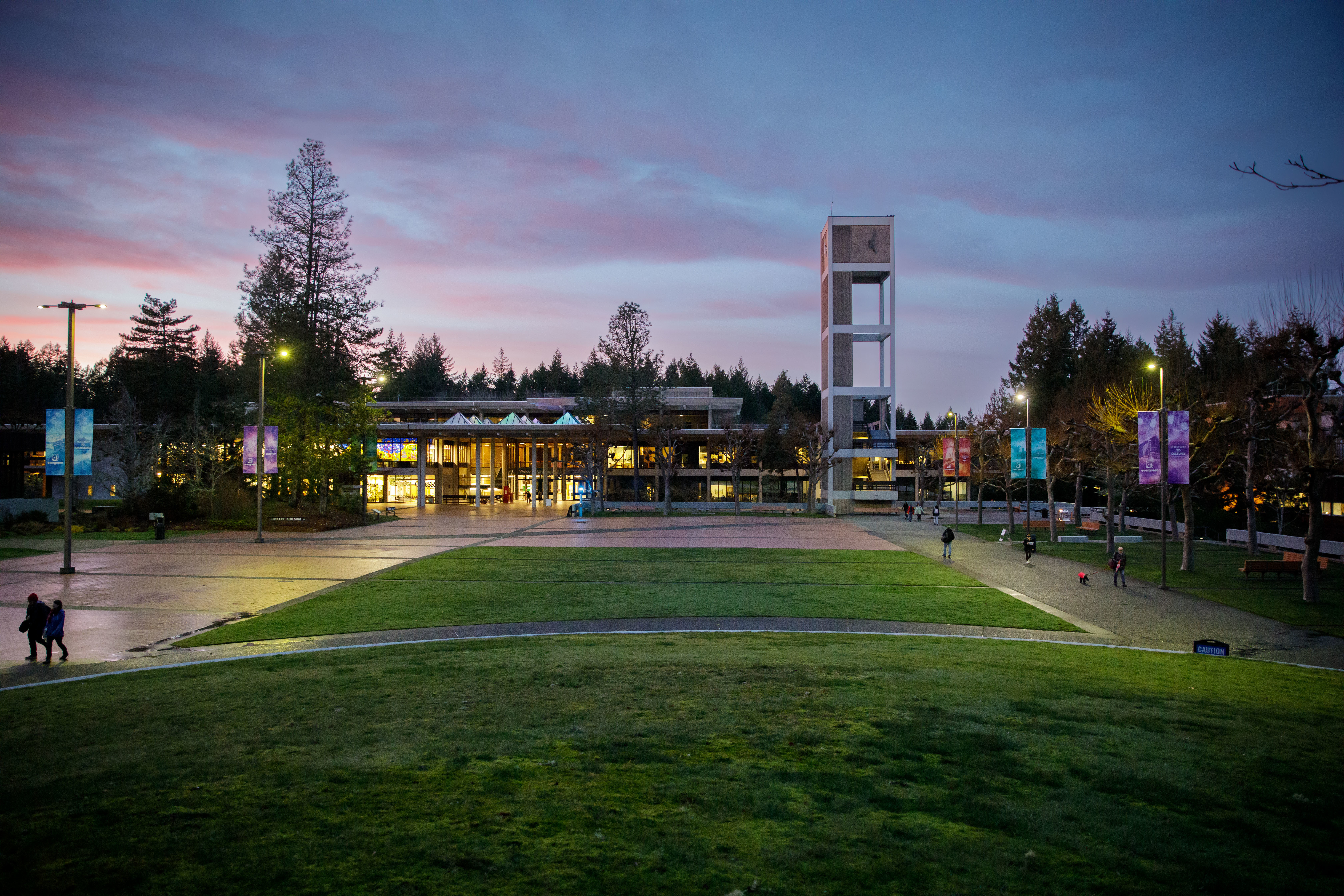 red square at sunset, the clocktower and evans hall are backlit by a purple sky, the square is dark and the grass is green as if it had just rained