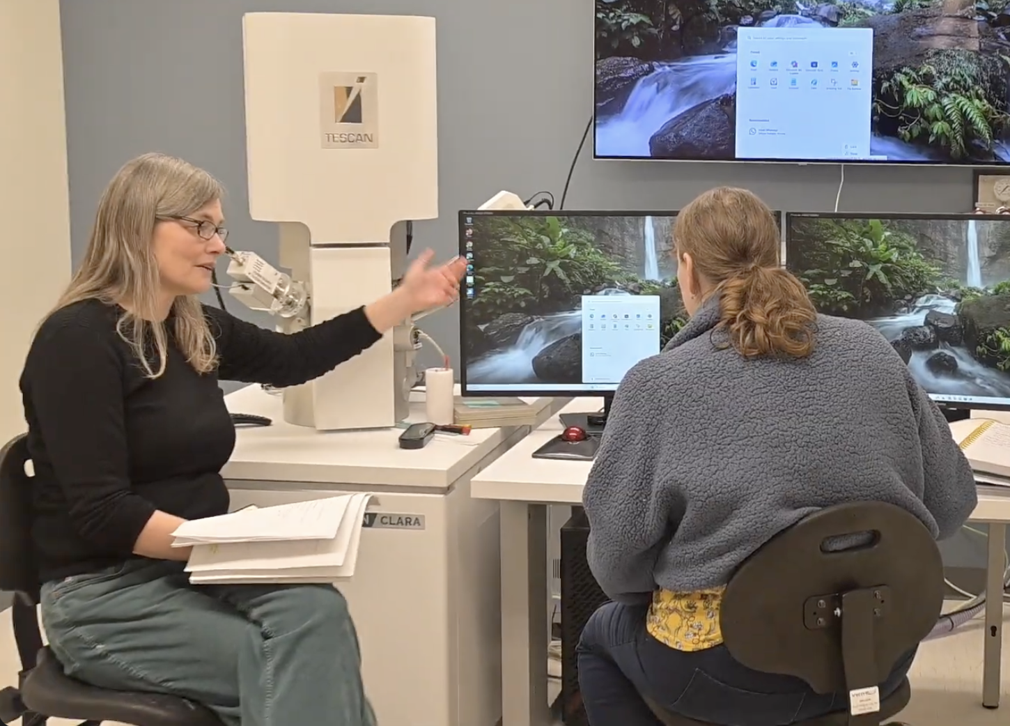 A lab technician at Evergreen instructing a student on how to use the new scanning electron microscope