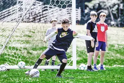 four kids playing soccer at camp speedy