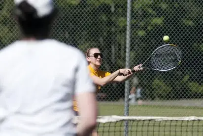 Two people playing tennis on a sunny day