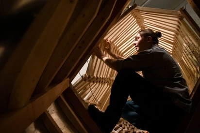 person assembling a sculpture of wood from inside