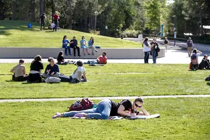 students sitting in the grass on red square