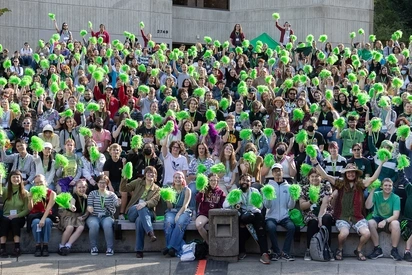 Hundreds of Evergreen Students seated in a group waving green pom poms.