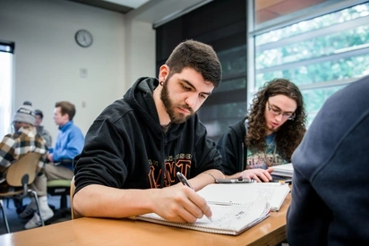 A student works on accounting and mathematics in a notebook