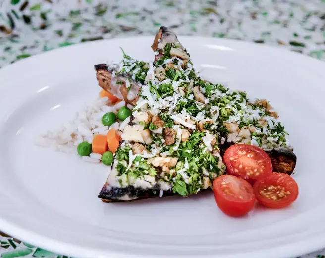 Close up of almond crusted tofu and rice with sliced cherry tomatos on a white plate