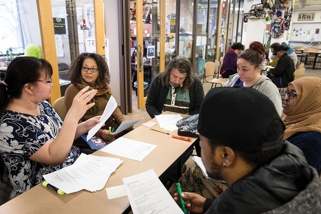 Group of six diverse students seated at a table having a discussion