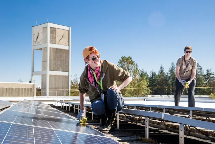 a student cleaning solar panels on roof of Evans Hall