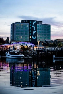 Waterfront view of tugboat and apartment building adorned with salmon art